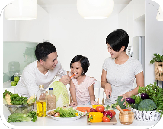 A family is sitting at the table with vegetables.
