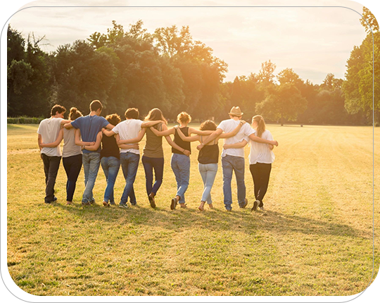 A group of people standing in the grass holding hands.